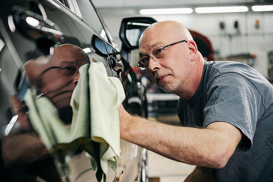 Ein Techniker mit Brille poliert in einer professionellen Werkstatt sorgfältig das Äußere eines Toyota-Fahrzeugs und verwendet dabei ein Mikrofasertuch, das die glatte Oberfläche widerspiegelt. Frey Auto AG ist auf umfassende Autoservices spezialisiert, darunter MFK-Inspektionen, Reifenservice, Karosseriereparaturen und gründliche Autowäsche. Wir sind stolz darauf, fachmännische Wartung für Toyota-, Lexus- und Suzuki-Fahrzeuge anzubieten, um optimale Leistung und ästhetische Exzellenz zu gewährleisten.
