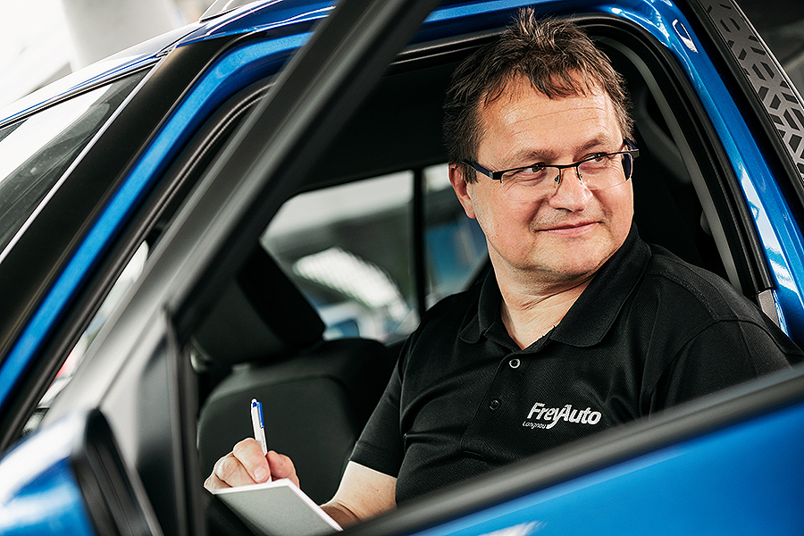 Ein Techniker der Frey Auto AG sitzt auf dem Fahrersitz eines blauen Autos und hält einen Stift und einen Notizblock in der Hand. Er trägt ein schwarzes Poloshirt mit dem Logo der Frey Auto AG, das ihr Engagement für erstklassige Kfz-Dienstleistungen wie MFK-Inspektion, Reifenservice und Karosseriearbeiten widerspiegelt. Das Fahrzeug repräsentiert renommierte Marken, die von der Frey Auto AG gewartet werden, darunter Toyota, Lexus und Suzuki. Diese Szene unterstreicht den professionellen und sorgfältigen Ansatz der Frey Auto AG beim Autoverkauf und bei der Wartung.