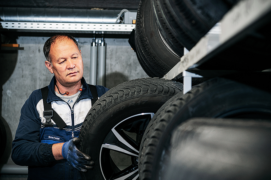 Ein Techniker mit Handschuhen untersucht eine Auswahl von Autoreifen auf einem Gestell in einem Servicecenter der Frey Auto AG. Die auf Toyota-, Lexus- und Suzuki-Fahrzeuge spezialisierte Frey Auto AG bietet umfassende Reifenservices einschließlich Austausch und Rotation. Die Werkstatt bietet sorgfältige MFK-Inspektionen zur Sicherstellung der Verkehrssicherheit, fachmännische Karosseriereparaturen für unfallgeschädigte Fahrzeuge und effiziente Autowaschanlagen für alle Automarken.