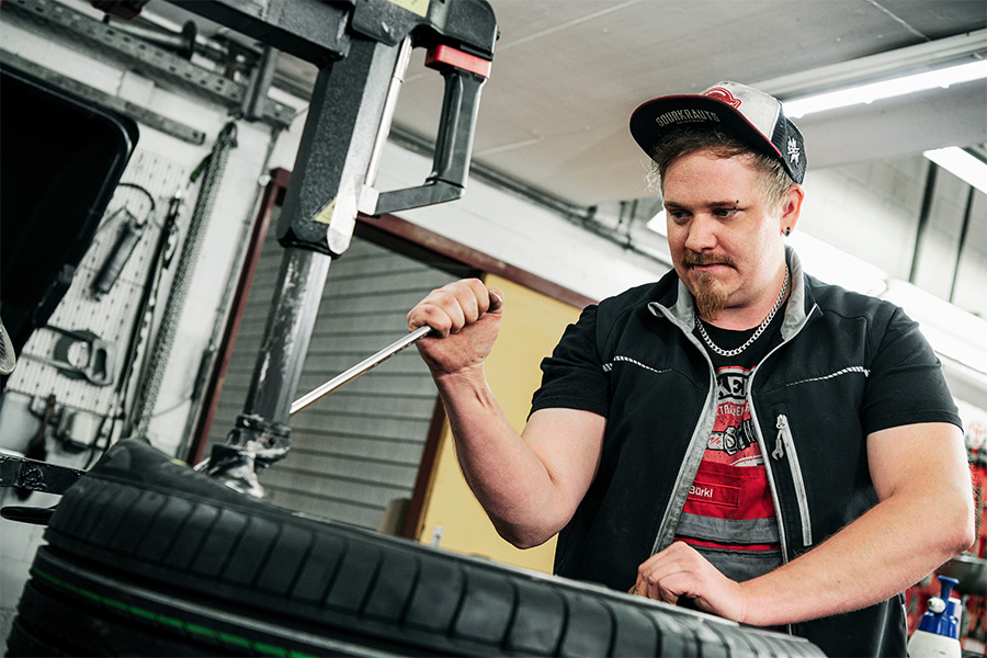 Mechaniker bei der Frey Auto AG, die auf die Wartung von Toyota-, Lexus- und Suzuki-Fahrzeugen, MFK-Prüfungen sowie professionelle Kfz-Reparaturen spezialisiert ist, führt mit Hilfe einer Reifenwechselmaschine einen Reifenservice durch.