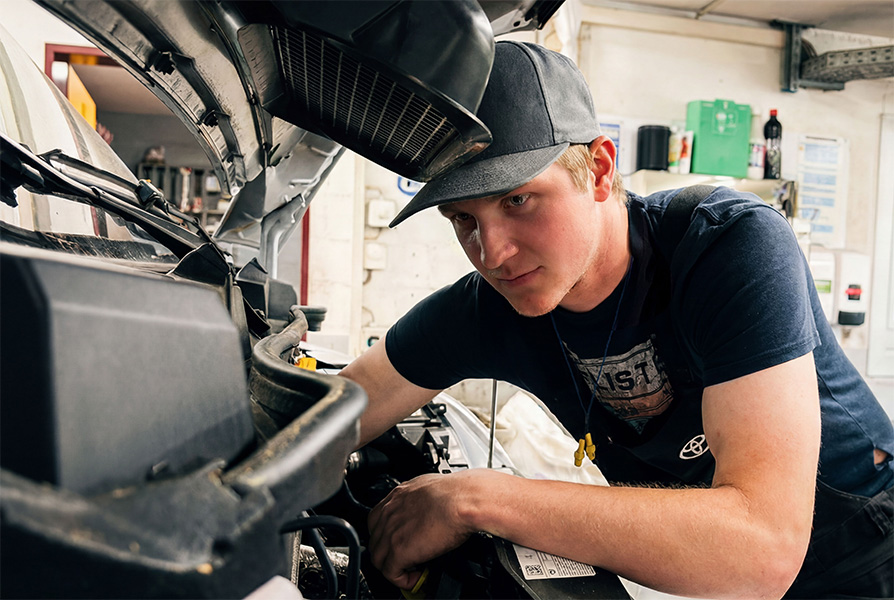 Ein Mechaniker der Frey Auto AG, der ein T-Shirt mit dem Toyota-Logo trägt, führt in der Werkstatt, die auf die Wartung von Toyota-, Lexus- und Suzuki-Fahrzeugen spezialisiert ist, eine professionelle Motorwartung durch.