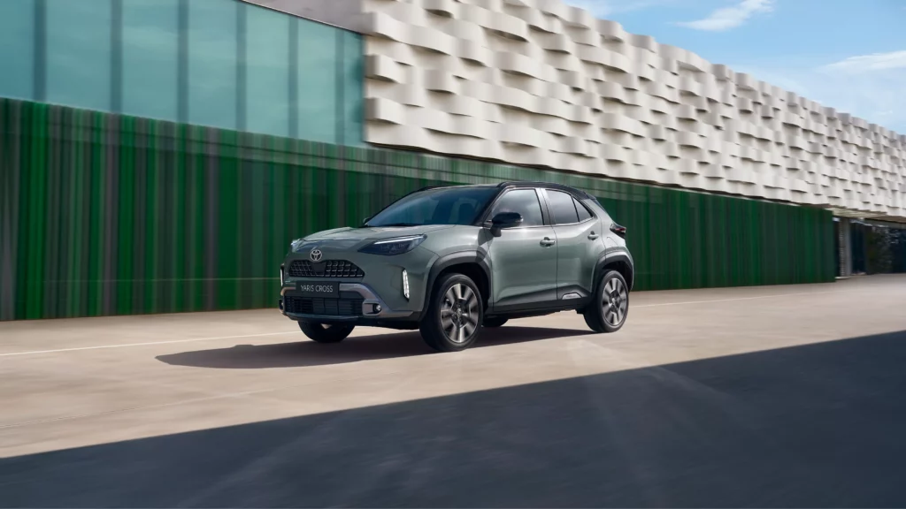 Grauer Toyota SUV fährt auf einer Straße neben einem modernen, strukturierten Gebäude unter einem klaren blauen Himmel. Dieses Fahrzeug ist ein Beispiel für das umfangreiche Autoverkaufsangebot der Frey Auto AG, das hochwertige Marken wie Toyota, Lexus und Suzuki umfasst. Das Bild unterstreicht die Eleganz und Zuverlässigkeit, die mit diesen Marken verbunden werden, unterstützt durch die umfassenden Dienstleistungen der Frey Auto AG, darunter MFK-Inspektion, professioneller Reifenservice, sorgfältige Karosseriereparaturen und praktische Autowaschanlagen.
