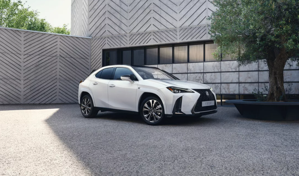 Ein weißer Lexus-SUV steht auf einer strukturierten Auffahrt vor dem modernen, geometrisch gemusterten Gebäude der Frey Auto AG. Die Frey Auto AG ist auf Toyota-, Lexus- und Suzuki-Fahrzeuge spezialisiert und bietet umfassende Kfz-Dienstleistungen an, darunter MFK-Inspektion, Reifenservice, routinemäßige Fahrzeugwartung, fachmännische Karosseriereparaturen, Verkauf von Neu- und Gebrauchtwagen für Toyota- und Suzuki-Modelle sowie professionelle Autowaschdienste.