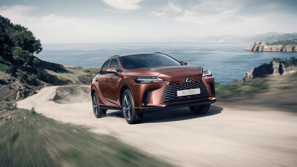 Kupferfarbener Lexus RX 350h fährt auf einer Küstenstraße und präsentiert Luxus und Leistung von Frey Auto AG. Der Ozean im Hintergrund unterstreicht das erstklassige Lexus-Design. Entdecken Sie bei Frey Auto AG fachmännische MFK-Inspektion, Reifenservice, umfassenden Fahrzeugservice, Karosserielösungen und Autoverkauf für Lexus-Modelle. Umfangreiche Serviceleistungen für Toyota- und Suzuki-Fahrzeuge. Erleben Sie eine nahtlose Nachsorge einschließlich Autowaschkompetenz in unserem auf Top-Automobilmarken spezialisierten Autohaus.