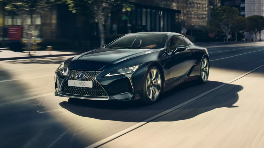 Ein eleganter schwarzer Lexus LC 500h Hybrid fährt auf einer sonnenbeschienenen Stadtstraße und demonstriert Luxus und dynamische Leistung. Besuchen Sie Frey Auto AG für umfassende Lexus-Services, einschließlich MFK-Inspektion, Reifenservice und fachmännischer Karosseriearbeit. Entdecken Sie Neu- und Gebrauchtwagenverkäufe von Top-Marken wie Toyota und Suzuki. Genießen Sie erstklassige Autowaschservices, die auf Ihr Luxusfahrzeug zugeschnitten sind.