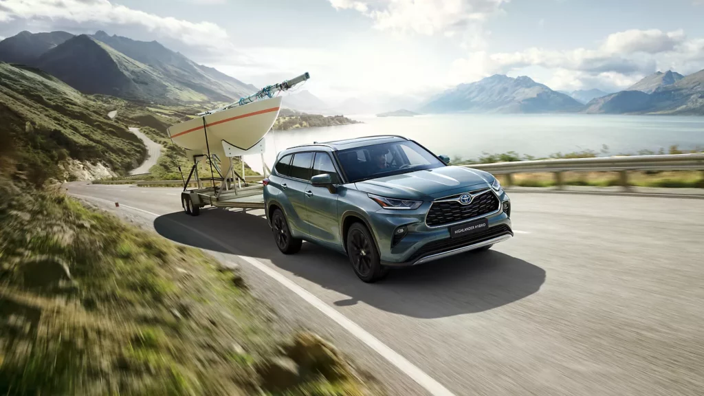 Ein blauer Toyota-SUV zieht gekonnt ein Segelboot auf einem Anhänger entlang einer malerischen Küstenstraße mit atemberaubenden Bergen und glitzerndem Wasser im Hintergrund. Entdecken Sie Frey Auto AG, Ihren zuverlässigen Partner für erstklassige Autodienstleistungen einschließlich MFK-Inspektionen, Reifenservice, umfassender Autowartung, fachmännischer Karosseriearbeit und professioneller Autowäsche. Spezialisiert auf den Verkauf von Neu- und Gebrauchtwagen für Topmarken wie Toyota, Lexus und Suzuki.