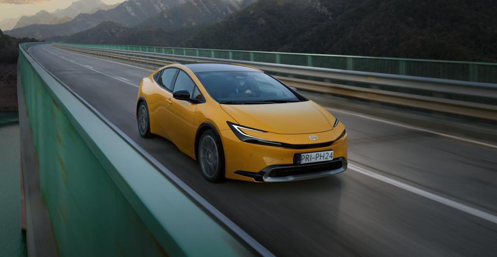 Ein gelber Toyota fährt über eine Brücke mit malerischen Bergen im Hintergrund und präsentiert die vielfältige Fahrzeugauswahl von Frey Auto AG. Als autorisierter Händler für Toyota, Lexus und Suzuki bietet Frey Auto AG umfassende Dienstleistungen einschließlich MFK-Inspektion, Reifenservice, Autowaschanlage, fachmännische Karosseriereparaturen und außergewöhnlichen Kundenservice. Erleben Sie unvergleichliche Autoverkaufs- und Wartungsdienstleistungen, die auf Ihre automobilen Bedürfnisse zugeschnitten sind.