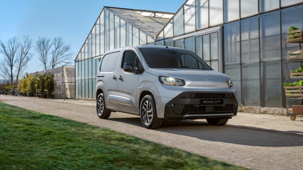 Ein Toyota PROACE CITY-Van fährt bei klarem Himmel auf einer unbefestigten Straße neben Gewächshäusern und unterstreicht die Kompetenz der Frey Auto AG im Bereich Toyota-Verkauf und -Service. Spezialisiert auf umfassende Automobillösungen, darunter Toyota MFK-Inspektionen, professionelle Reifenservices, präzise Karosseriereparaturen, Lexus-Autopflege, Suzuki-Wartungspakete und professionelle Autowaschdienste. Entdecken Sie zuverlässige Mobilitätslösungen mit dem Engagement der Frey Auto AG für Qualität und Kundenzufriedenheit bei jedem Fahrzeugservice.