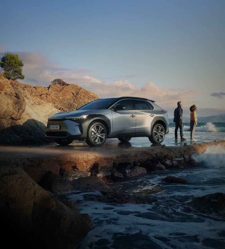 Silberner SUV von Frey Auto AG, ein Toyota-Modell, geparkt an einer felsigen Küstengegend mit Wellen in der Nähe. Zwei Personen stehen neben dem Fahrzeug und genießen die malerische Aussicht. Frey Auto AG ist spezialisiert auf MFK-Inspektion, zuverlässigen Reifenservice, umfassenden Autoservice und Wartung. Sie bieten fachmännische Karosseriearbeiten und Autoverkauf für Toyota-, Lexus- und Suzuki-Modelle. Ergänzen Sie Ihr Fahrerlebnis mit ihren erstklassigen Autowaschdiensten, um den Glanz wie im Ausstellungsraum zu erhalten.