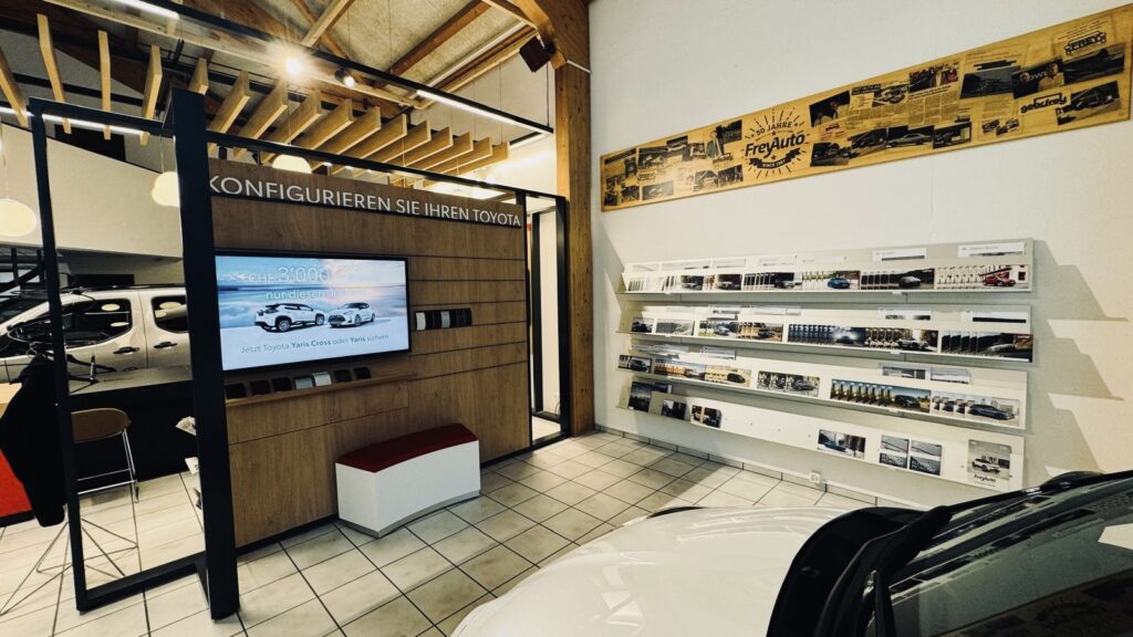 Toyota-Autohaus der Frey Auto AG mit Konfigurationsstation für die Individualisierung von Toyota-, Lexus- und Suzuki-Fahrzeugen; Wanddisplay mit den neusten Automodellen; grosse Fotocollage mit MFK-Inspektion, Reifenservice, professionellem Fahrzeugservice, fachgerechter Karosseriereparatur, Neu- und Gebrauchtwagenverkauf und Waschanlage vor Ort.