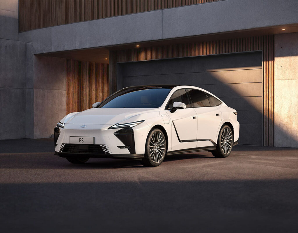 Eine weiße Lexus ES-Limousine steht vor der modernen Werkstatt der Frey Auto AG, die sich auf den Verkauf von Toyota, Lexus und Suzuki, die MFK-Prüfung, den Reifenservice, Wartungsarbeiten und Karosseriereparaturen spezialisiert hat.