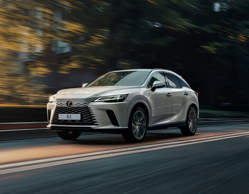 Ein silberner Lexus RX SUV fährt auf einer Straße, wobei Bewegungsunschärfe zu sehen ist – dies symbolisiert den Verkauf von Premium-Fahrzeugen, den umfassenden Service und die fachkundige Wartung der Frey Auto AG.