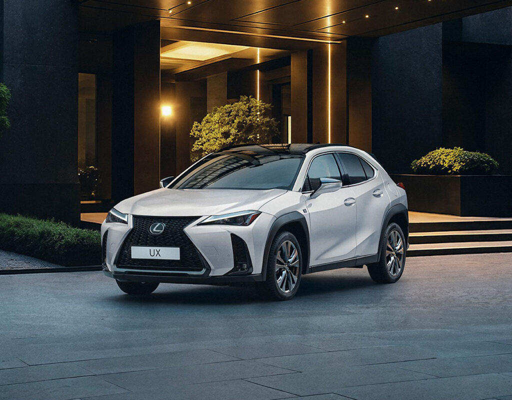 Ein weißer Lexus UX steht vor dem Eingang der modernen Niederlassung der Frey Auto AG, die als unser professionelles Autohaus und autorisiertes Servicezentrum für Toyota, Lexus und Suzuki fungiert.