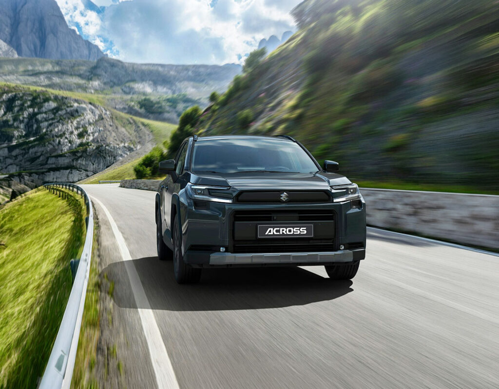 Ein dunkelgrauer Suzuki Across SUV, der über den Autohandel der Frey Auto AG erhältlich ist, fährt auf einer Bergstraße.