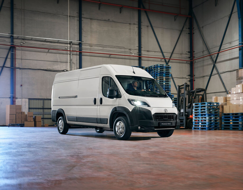 Ein weißer Toyota Proace Max Transporter fährt durch ein Lager der Frey Auto AG und steht symbolisch für unsere Kompetenz in den Bereichen professioneller Fahrzeugservice, Karosseriearbeiten und Verkauf von Fahrzeugflotten.